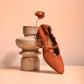 Brown ballet shoe with a flower on a pink background