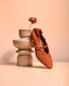 Brown ballet shoe with a flower on a pink background