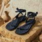 Pair of black sandals on a stone surface with rustic decor
