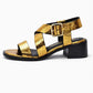 Gold and black sandal with a block heel on a white background