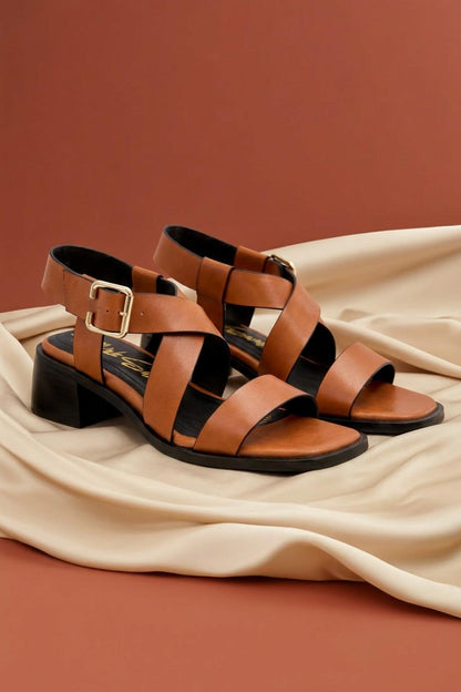 Brown sandals with black soles on a beige fabric background